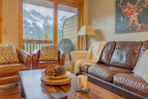 a living room with leather couches and a table at Rundle Range Retreat Lux Mtn View Condo near dt in Canmore