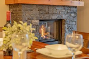 a table with wine glasses and a fireplace at Rundle Range Retreat Lux Mtn View Condo near dt in Canmore