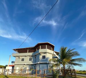 een wit huis met een palmboom ervoor bij Pousada Recanto Vila Viçosa in Nova Viçosa