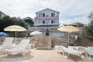 a group of chairs and umbrellas in front of a house at Apartments Atlas Grubišić in Primošten