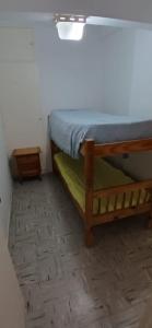 een kleine slaapkamer met een bed en een houten vloer bij Frente al mar in Miramar