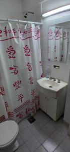 een badkamer met een toilet, een wastafel en een douchegordijn bij Frente al mar in Miramar