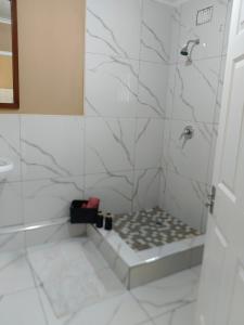 a bathroom with a shower with white tiles at The Glen House in Durban
