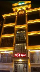 un edificio alto con insegne al neon davanti di Madina plaza a Kabul