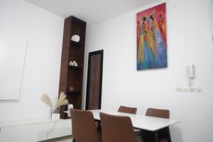a white dining room with a table and chairs at SEJOURABIDJAN - Residences Cocody Angré in Abidjan