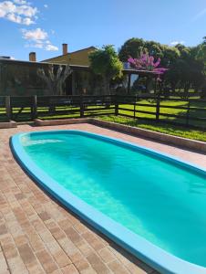 a swimming pool in a yard with a fence at Chácara Alci Guedes in São Gabriel