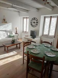 a living room with a table and chairs and a clock at Le gîte des Bernadettes in Apchat