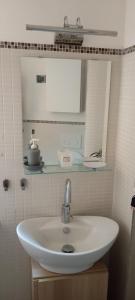 un lavandino bianco in un bagno con uno specchio di Loft Mansardato a Catania