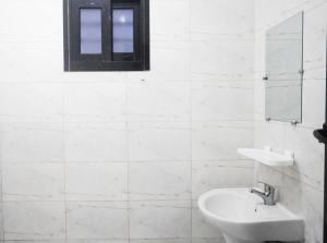 a white bathroom with a sink and a mirror at SEJOURABIDJAN - Residences Cocody Angré in Abidjan