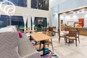 una sala de estar con sofá, mesas y sillas en Hampton Inn & Suites Pensacola/I-10 Pine Forest Road, en Pensacola
