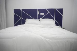 a large white bed with a blue and white headboard at SEJOURABIDJAN - Residences Cocody Angré in Abidjan
