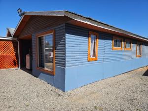a small house with a blue exterior with windows at Ribera del Ancoa in Llepu
