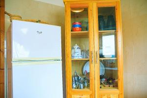 een houten kast met servies erin naast een koelkast bij CAN Comfort Residence in Temara