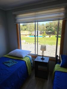 a bedroom with two beds and a large window at Ribera del Ancoa in Llepu