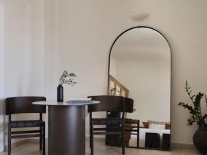 Un comedor con una mesa y sillas y un espejo. en San Antonio - Small Luxury Hotels of the World, en Imerovigli