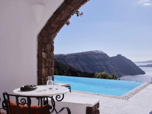 una mesa y sillas junto a una piscina en San Antonio - Small Luxury Hotels of the World, en Imerovigli