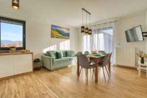 a living room with a table and a couch at Wakacyjne Historie - nowoczesne i komfortowe apartamenty ze SPA u podnóża Śnieżnika in Międzylesie