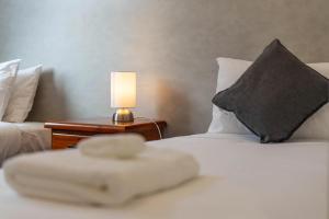 a bed with a pillow and a lamp on a table at Remarkable Cross Road Retreat in Frankton