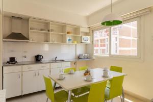 a kitchen with a table and green chairs at Le Batiment Apartments in Buenos Aires