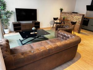 a living room with a brown couch and a tv at L'Escale Saint-Martin in Laon