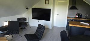 a living room with a flat screen tv and chairs at Apartment Feelgood in Billdal