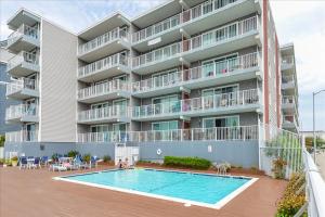 a large apartment building with a swimming pool in front of it at Amazing Bay view from this Assateague House Condo in Ocean City