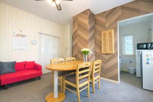 een eetkamer met een tafel en een rode bank bij Yume House in Furano