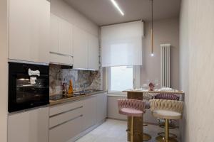 a kitchen with white cabinets and pink stools at AlexandraDesignSuite -Eleganza a due passi dal centro in Carpi