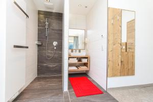 a bathroom with a shower and a red rug at Eberharthof in Saalbach-Hinterglemm