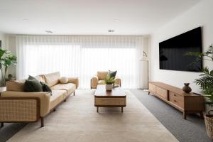 een woonkamer met een bank en een tv bij Bahagia Oasis in Safety Beach