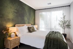 een slaapkamer met een wit bed en een groene muur bij Bahagia Oasis in Safety Beach +26 foto's