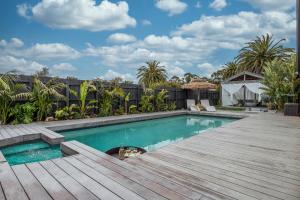 een zwembad met een houten terras naast een achtertuin bij Bahagia Oasis in Safety Beach