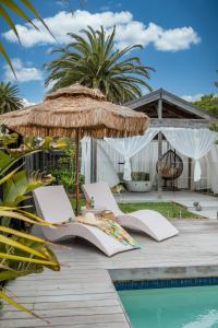 een terras met stoelen, een parasol en een zwembad bij Bahagia Oasis in Safety Beach