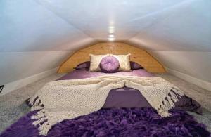 ein Bett mit einer lila Bettdecke in einem kleinen Zimmer in der Unterkunft The Huckleberry A Teton Tiny Home in Driggs