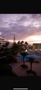 Blick auf einen Pool mit Palmen und Sonnenuntergang in der Unterkunft ¡Tal y como Hawaii! in Playa Fañabe