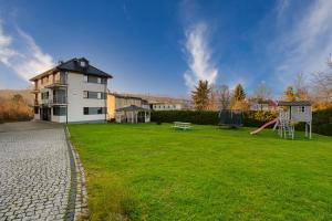 a large house with a playground in a yard at Wakacyjne Historie - nowoczesne i komfortowe apartamenty ze SPA u podnóża Śnieżnika in Międzylesie