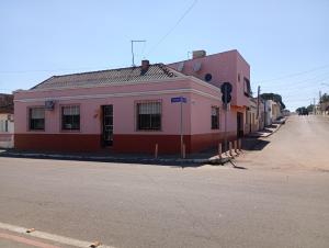 a red and pink building on the side of a street at Posada domiciliar DB in São Gabriel
