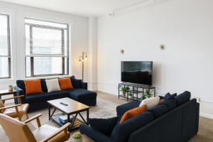 a living room with two blue couches and a tv at Spacious Loft with Fireplace - near CSU, Playhouse, Progressive field, R&R Hall of Fame with Gym & Sauna and Sleeps 12 in Cleveland