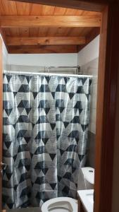 un bagno con un water e una tenda da doccia di Cabaña El Atardecer 2 a Necochea