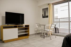 a living room with a tv and a table and chairs at Loft Rio - Ideal turismo - Opcion a cochera! in Rosario