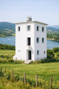 a white house on a hill with a body of water at Lala Elyacout in Azzaba