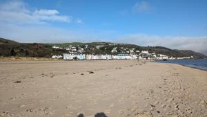 a beach with footprints in the sand and buildings in the background at Neifion in Aberdyfi