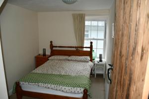 a bedroom with a bed with a green and white comforter at Neifion in Aberdyfi