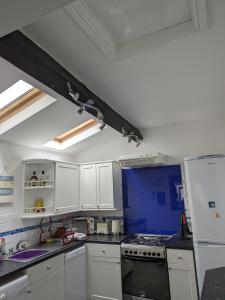 a kitchen with white cabinets and a blue wall at Neifion in Aberdyfi