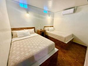 two beds in a small room with blue lights at Comod Inn in Manuel F. Martínez