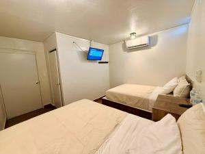a small room with two beds and a television at Comod Inn in Manuel F. Martínez +8 photos