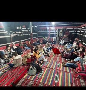 eine Gruppe von Menschen, die auf dem Boden sitzen in der Unterkunft חאן לקיה in Kramim