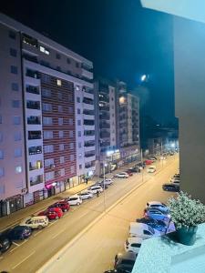una vista de la ciudad por la noche con coches aparcados en City View Apartment, en Kosovska Mitrovica