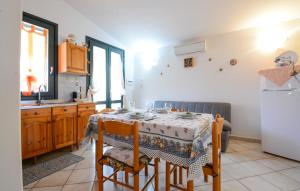 a kitchen with a table and a white refrigerator at Lovely Apartment In Sant'antioco With Wifi in SantʼAntìoco +4 photos