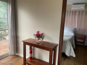 uma pequena mesa com um vaso de flores ao lado de um quarto em K S G Cabanas em Dangriga